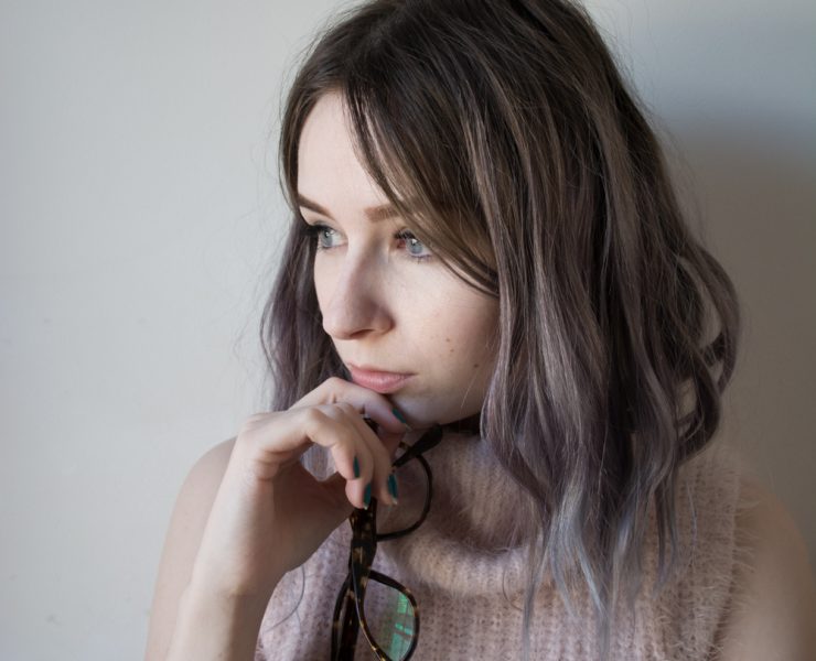girl holding glasses and wearing pink fluffy jumper