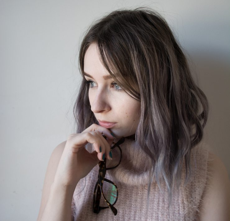 girl holding glasses and wearing pink fluffy jumper