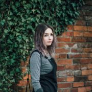 girl stood in front of red brick wall wearing primark pinafore dress