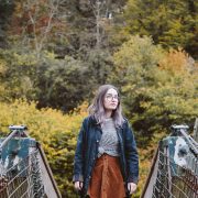 girl stood on bridge in front of autumn trees