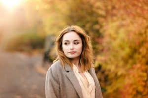 portrait of a girl wearing a silk shirt standing amongst autumn leaves. how to pose for photos