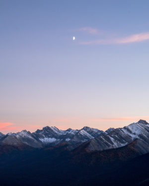the view from sulfur mountain in banff, canada, of a half moon and snow capped mountains
