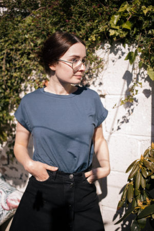 girl wearing navy blue t shirt and black denim skirt stood in garden