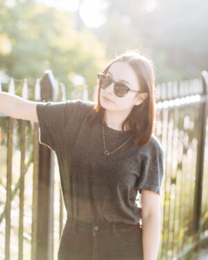 girl wearing sunglasses standing in street, backlit by the sun. Sustainable sunglasses pala eyewear