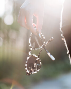 hand holding tortoiseshell sunglasses, backlit by the sun. Sustainable sunglasses pala eyewear