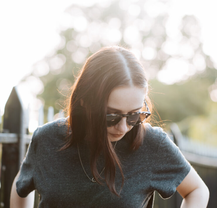 girl wearing sunglasses standing in street, backlit by the sun. Sustainable sunglasses pala eyewear
